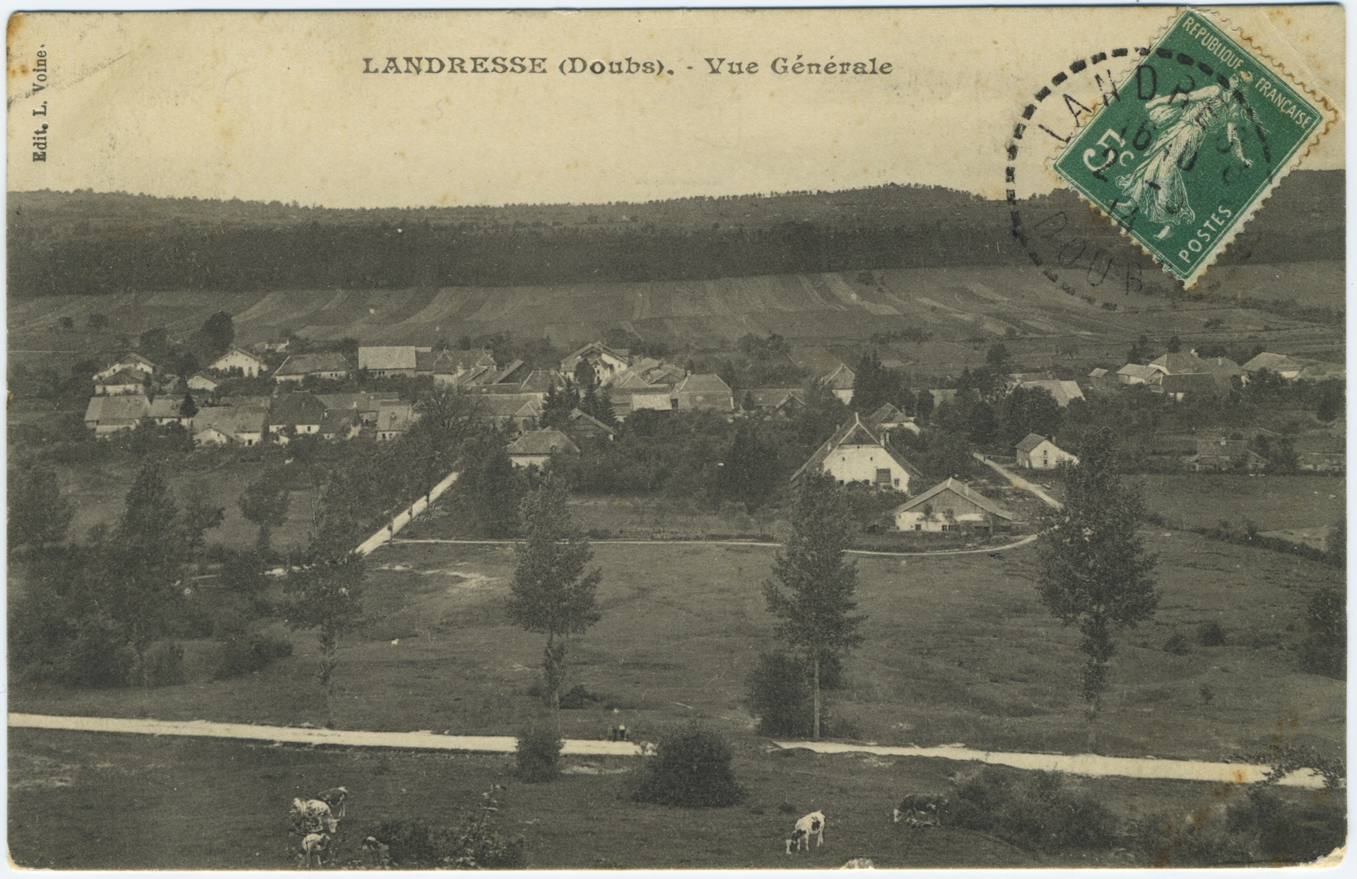 Photographie ancienne en vue aérienne de Landresse (Doubs). Le village est niché au milieu des champs et des bois. Au premier plan, des vaches paissent dans un pré. Un timbre vert de 5 centimes est oblitéré en haut à droite.