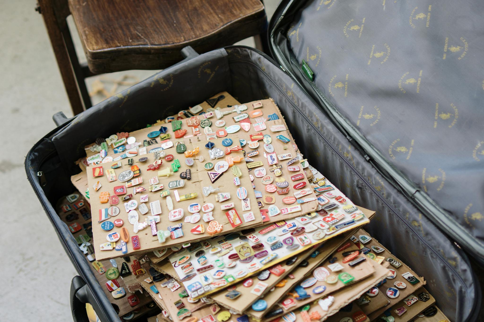 A diverse collection of vintage pins displayed in an open suitcase, showcasing travel and nostalgia themes.